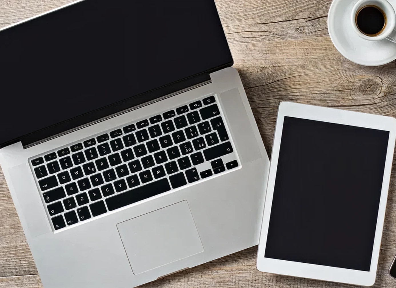 Laptop, tablet, and coffee on wooden table