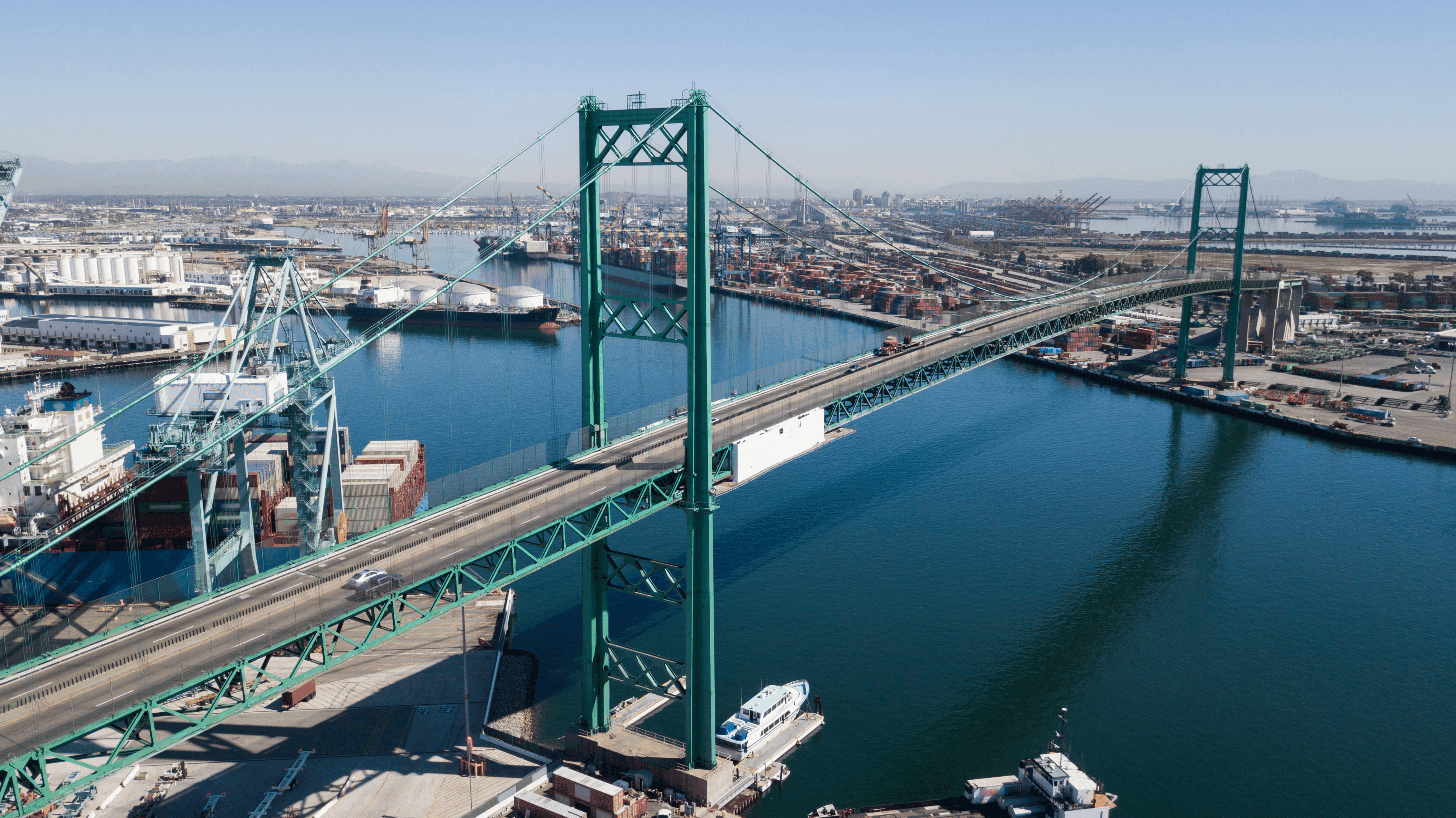 A large suspension bridge over a busy river in a cityscape.