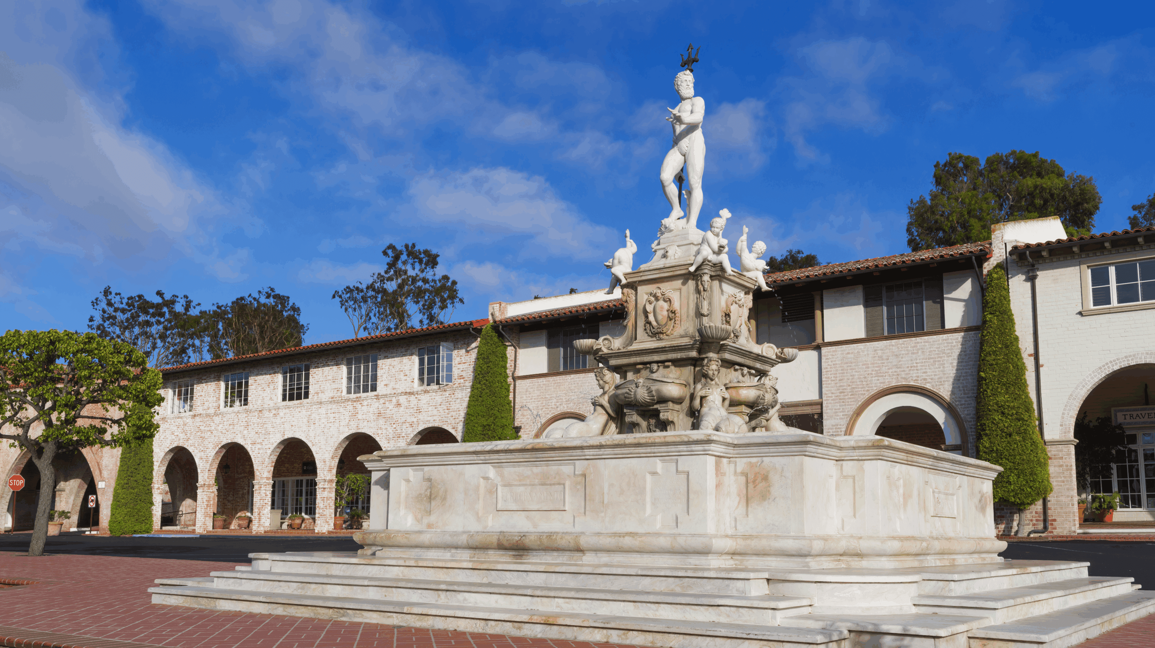 A classical marble fountain with a statue under a blue sky.